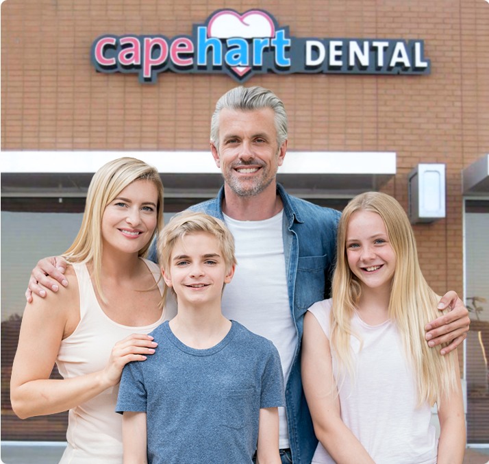 Smiling family of four standing outside Capehart Dental