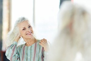 Woman admiring her dentures in the mirror