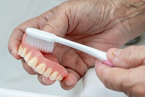 Close up of patient brushing their removable denture