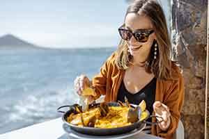 Smiling woman squeezing lemon on lunch on vacation