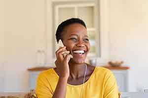 Woman in yellow shirt smiling while talking on phone