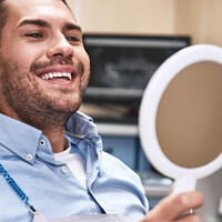 a patient checking his smile with a mirror