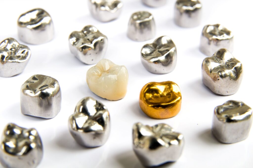 Several dental crowns of various materials on a white surface