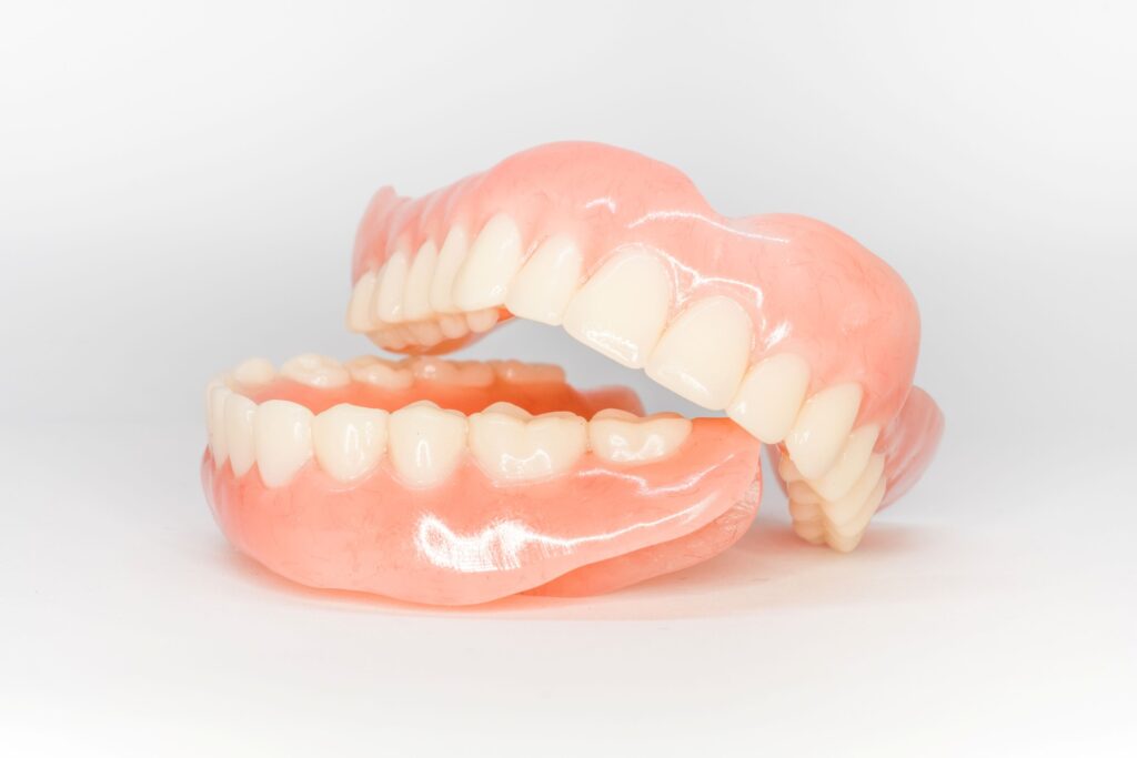 Upper arch of dentures resting on lower arch of dentures with white background