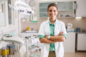 Dentist smiling brightly while standing in a treatment room